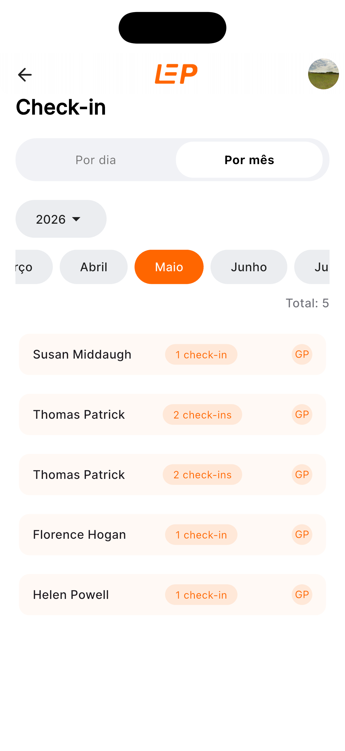 Tela de histórico de check-ins do LEP App, com tabs 'Por dia' e 'Por mês' (selecionada), seletor de ano 2026, lista de meses com 'Maio' destacado em laranja e check-ins listados com etiqueta de plataforma.